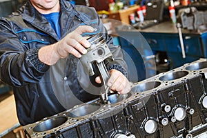 Diesel truck engine repair service. Automobile mechanic installing piston into engine photo