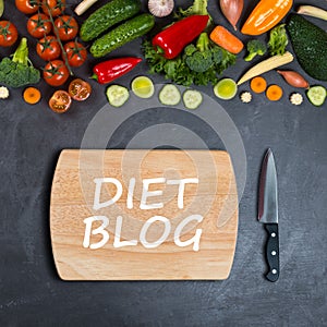 Diet blog concept. Vegetables, empty wooden cutting board and chef`s knife on a black background