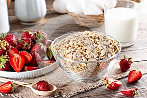 Diet breakfast - bowls of oat flake, berries and fresh milk on wooden background - health and diet concept