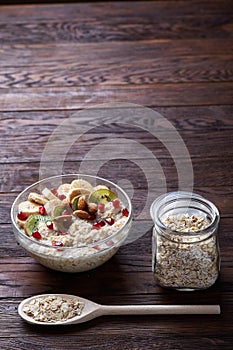 Diet breakfast oatmeal with fruits, bowl and spoon with oat flakes, selective focus, close-up