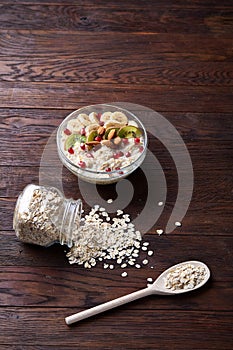 Diet breakfast oatmeal with fruits, bowl and spoon with oat flakes, selective focus, close-up