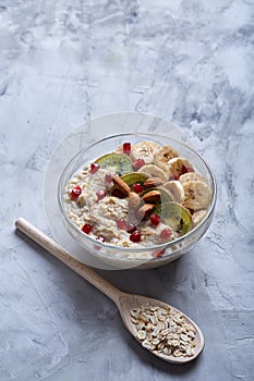 Diet breakfast oatmeal with fruits, bowl and spoon with oat flakes, selective focus, close-up