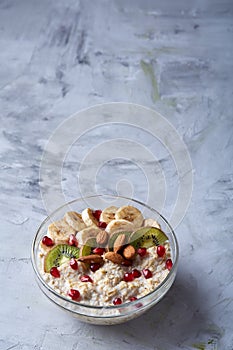 Diet breakfast oatmeal with fruits, bowl and spoon with oat flakes, selective focus, close-up