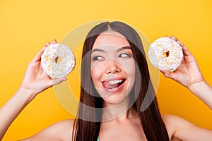 Diet and calories concept. Close up portrait of happy asian girl looking on donutes with tounge out, so playful and hungry. Pretty
