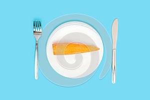 Diet. Carrots on a white plate standing on a blue background, top view