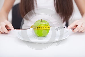 Diet. Close up photo of tape measure coiled around an apple on w