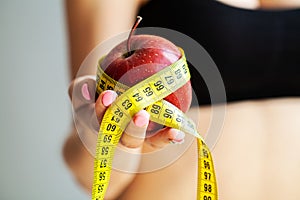 Diet concept. Apple with measure tape in female hand