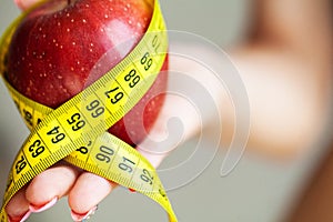 Diet concept. Apple with measure tape in female hand