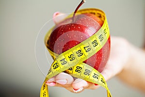 Diet concept. Apple with measure tape in female hand