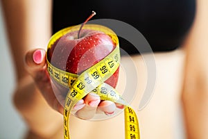 Diet concept. Apple with measure tape in female hand