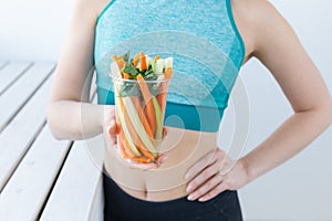 Diet concept - close-up of healthy lifestyle woman holding vegetables indoors. Young female eating healthy food.
