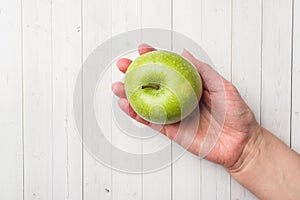Diet concept. green Apple rests in the palm of your hand on a white table