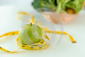Diet concept. Green apples and tape measure with with a gutsy salad on the table. Eating foods with high vitamins for health and w photo