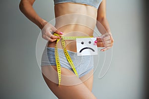 Diet concept. Hands measuring waist with a tape. Slim and healthy woman at her home