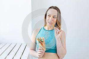 Diet concept - Healthy lifestyle woman eating vegetables smiling happy indoors. Young female eating healthy food.