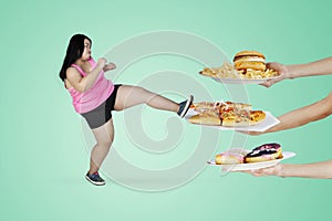 Obese woman kicking unhealthy foods