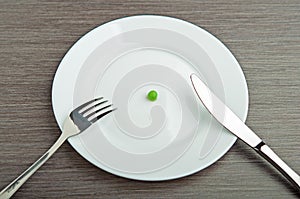 Diet concept. one pea on an empty white plate