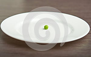 Diet concept. one pea on an empty white plate photo