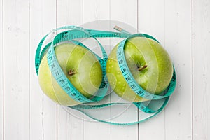 Diet concept. Two green Apples and a roulette wheel on a white table