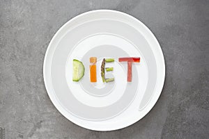 Diet concept. White plate with word - diet - composed of slices of different fruits and vegetables