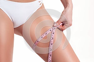 Diet concept, woman measuring her leg with a measure tape