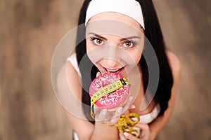 Diet Concept. Young Woman Measuring Body Weight On Weighing Scale While Holding Glazed Donut With Sprinkles. Sweets Are Unhealthy