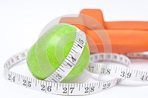 Diet diabetes weight loss concept with tape measure organic green apple and yellow dumbbels on a white background