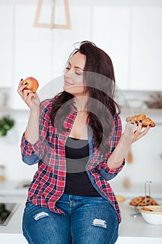 Diet. Dieting concept. Healthy Food. Beautiful Young Woman choosing between Fruits and Sweets. Weight Loss