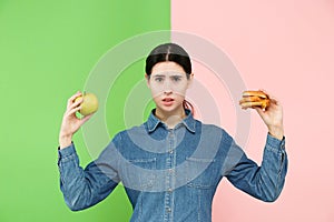 Diet. Dieting concept. Healthy Food. Beautiful Young Woman choosing between fruits and unhelathy fast food