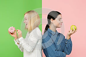 Diet. Dieting concept. Healthy Food. Beautiful Young Women choosing between fruits and unhelathy cake