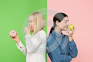 Diet. Dieting concept. Healthy Food. Beautiful Young Women choosing between fruits and unhelathy cake