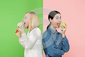 Diet. Dieting concept. Healthy Food. Beautiful Young Women choosing between fruits and unhelathy cake