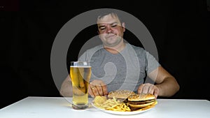 Diet failure of fat man eating fast food hamberger. Happy smile overweight person who spoiled healthy food by eating