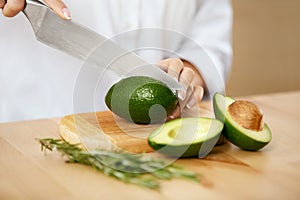Diet. Female Hands Cutting Avocado In Kitchen.