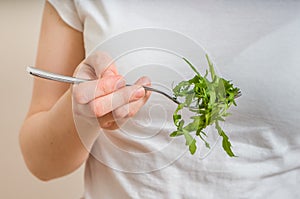 Diet and healthy eating concept. Young vegetaian woman is eating ruccola.