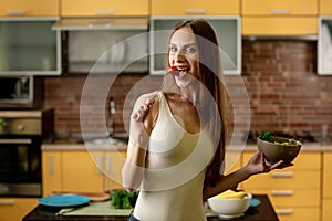 Diet, healthy eating concept. Young woman eating cherry tomatoes and holds a bowl of salad
