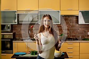 Diet, healthy eating concept. Young woman holding a fork with cherry tomatoes and a bowl of salad