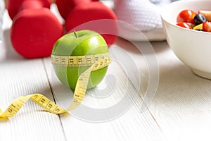 Diet and Healthy life loss weight Concept. Green apple and Weight scale measure tap with fresh vegetable and sport equipment for w