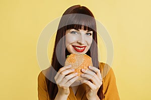 Diet and jank food concept. Portrait of young red haired beautiful hungry woman holding fresh hamburger and smiling to