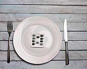 Diet or medicine abuse concept - green pills in plate with knif