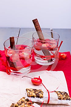 Diet muesli bars with detox apple cinnamon water on red pepper and wooden background.