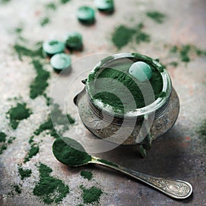 Superfood concept ground green spirulina algae powder, pills tablets photo