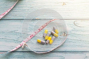 Diet Pills with measuring tape on  wooden background. Diet concept. Shallow Depth of field