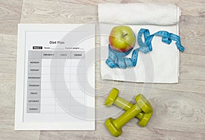 Diet plan, green weights, apple, measure tape and towel