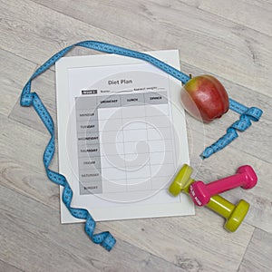 Diet plan, green weights, apple, measure tape and towel