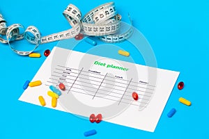 Diet plan and weight loss pills on blue background.