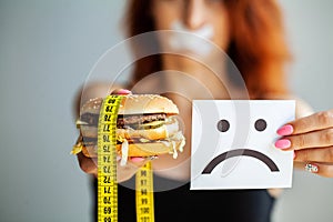 Diet. Portrait woman wants to eat a Burger but stuck skochem mouth, the concept of diet, junk food, willpower in