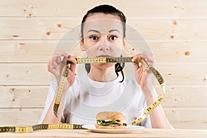 Diet. Portrait woman wants to eat a Burger but stuck skochem mouth, the concept of diet, junk food, willpower in nutrition