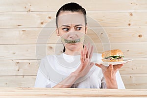 Diet. Portrait woman wants to eat a Burger but stuck skochem mouth, the concept of diet, junk food, willpower in nutrition