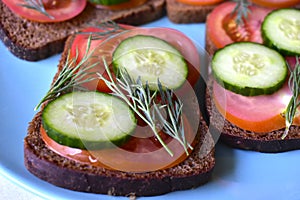 Diet sandwiches made of black flour with tomatoes and cucumber